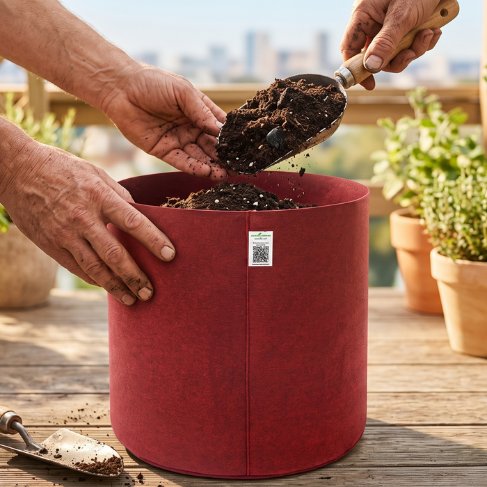A gardener filling a fabric grow bag with layered soil and compost on a terrace before planting