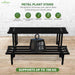 Metal plant stand with a 100 kg weight on a wooden surface, featuring Anandi Greens branding.
