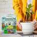 Person-holding-a-potted-plant-with-Anandi-Greens-potting-soil-mix-packaging.
