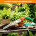 Gardening tools including a saw, gloves, and trowel on a wooden table with plants in the background. Tree cutting hand saw outdoor use